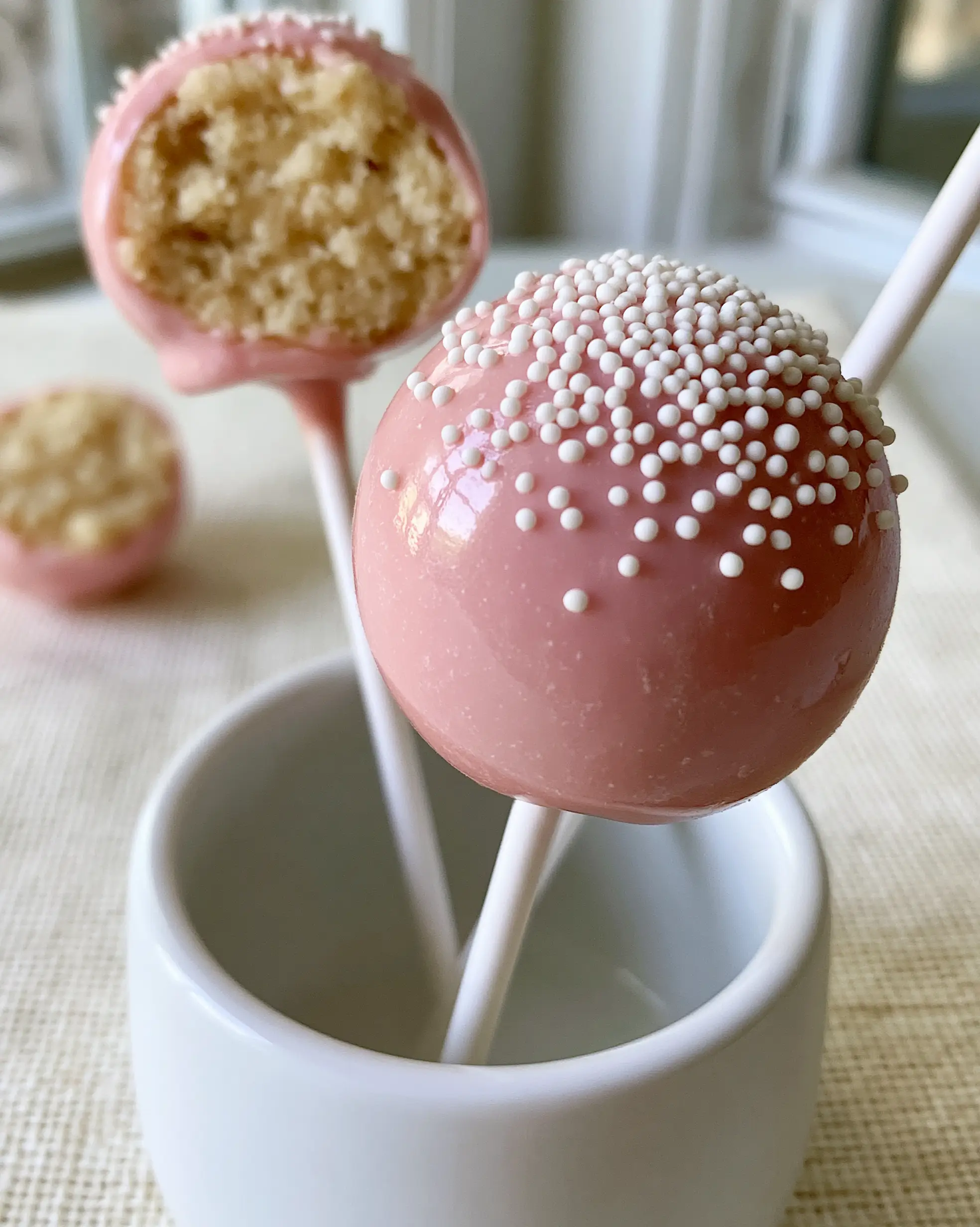 Cake Pop Recipes: The Ultimate Starbucks Copycat Guide 3 A handheld smartphone photo of a flawless Starbucks copycat pink cake pop showing an ultra-smooth glossy shell. (cake pop recipes)
