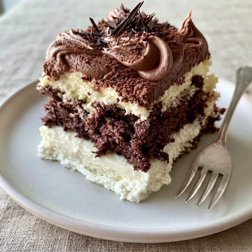 Side view of Italian Love Cake showing the whipped chocolate pudding frosting with elegant swoops and cocoa powder dusting.