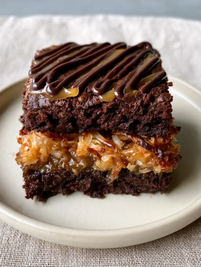 Samoa Brownies with Fudgy Chocolate and Toasted Coconut 2 Close-up handheld photo of thick dense fudgy chocolate samoa brownies with golden toasted shredded coconut flakes.