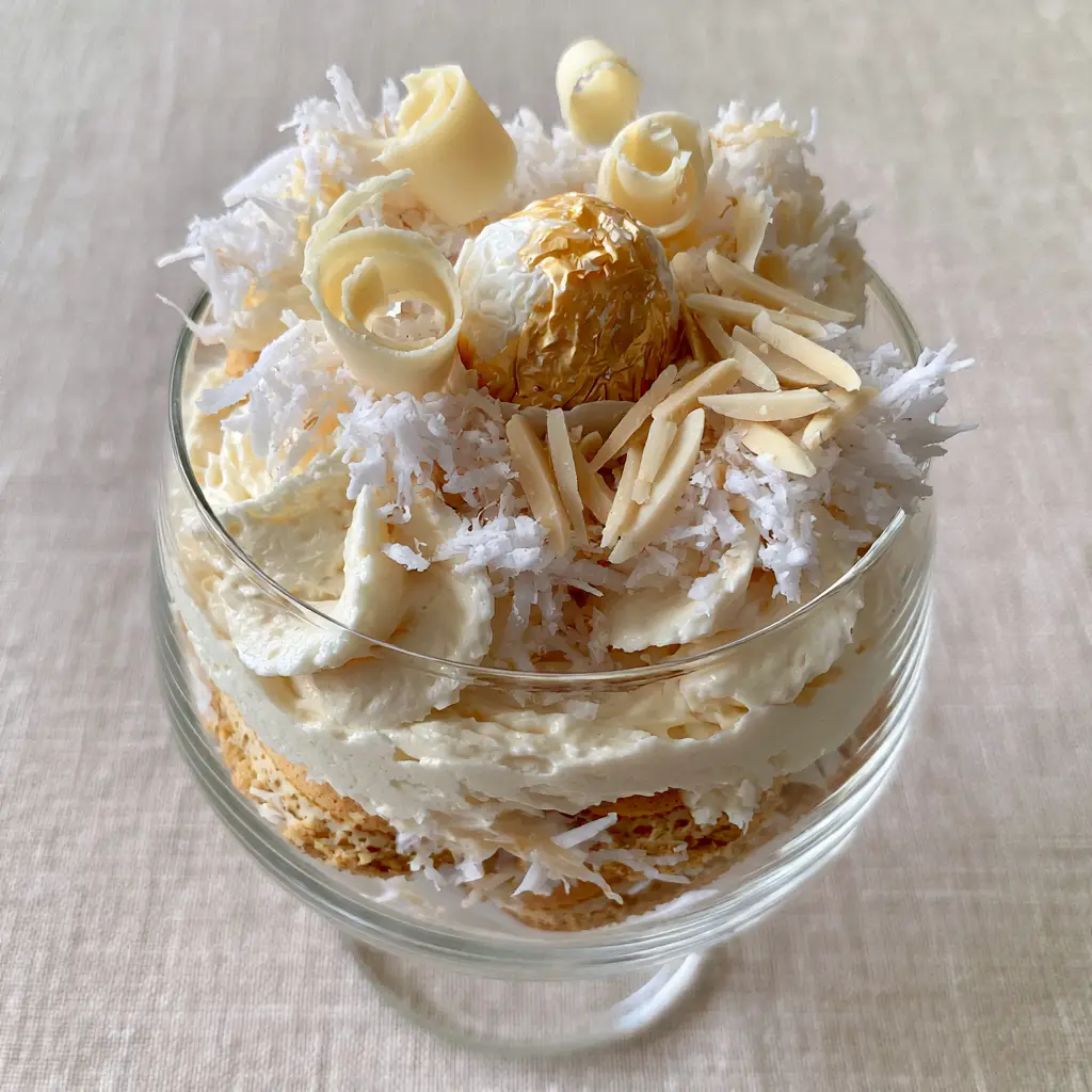 Raffaello Tiramisu: The Ultimate White Chocolate and Coconut Dessert 1 Top view of Raffaello Tiramisu garnished with a whole truffle and sliced blanched almonds on a linen background.